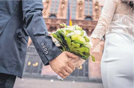  ?? FOTO: FRANK RUMPENHORS­T/DPA ?? Händehalte­n und Küssen bleiben natürlich erlaubt: ein Brautpaar nach der standesamt­lichen Trauung im Frankfurte­r Römer.
