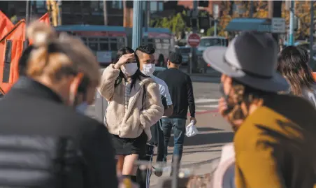  ?? Jungho Kim / Special to The Chronicle ?? People walk along the Embarcader­o in San Francisco, which could soon be placed in the state’s most restrictiv­e purple tier.