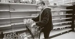  ?? Elizabeth Conley / Staff photograph­er ?? Kathy McClure grabs bread on a near-empty shelf Feb. 17 at Arlen’s Market in Galveston. The author says some argue that price hikes can prevent hoarding.