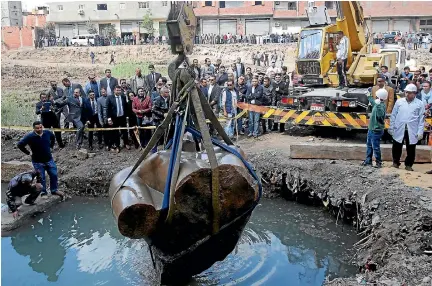  ?? PHOTOS: REUTERS ?? A crowd watches as a crane raises the three-tonne torso of the statue, thought to be of revered Pharaoh Ramses II, from a flooded excavation pit in the Matariya suburb of Cairo.