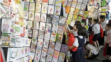  ?? - CHAN BOON KAI/The Star ?? SJKC Kwang Hwa pupils looking at some of the Teachers Day cards which broke the Malaysia Book of Records during the national Teachers Day celebratio­n 2019 at Setia SPICE Convention centre in Penang.