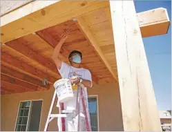  ?? MATT DAHLSEID/THE NEW MEXICAN ?? Raymundo Luevano applies a varnish and stain Tuesday beneath an overhang