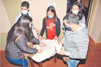  ??  ?? Jóvenes de la Pastoral Juvenil de la parroquia de San Ignacio elaboran los bolsos de tela.