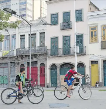  ?? PHOTOS: RENATA BRITO/THE ASSOCIATED PRESS ?? Boys ride their bikes in front of houses in Rio de Janeiro that, before 1888, were occupied by slaves arriving from Africa. Before abolishing slavery in 1888, becoming the last country in the Americas to do so, Brazil was the world’s largest slave...