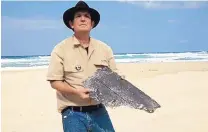  ?? BLAIN GIBSON/ASSOCIATED PRESS ?? Blaine Gibson holds a piece of aircraft debris on a beach in Madagascar. He is the first person searching for the missing Malaysian plane who has found any trace of it.