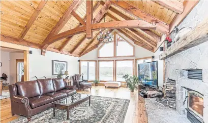  ??  ?? The living room has a beamed cathedral ceiling, a fireplace with a floor-to-ceiling stone surround and a palladium window.