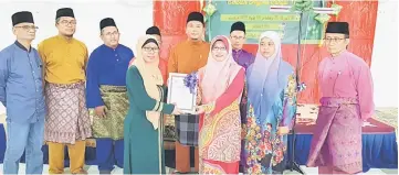  ??  ?? Marini (third right) presents the ‘wakaf’ certificat­e to the school’s wakaf chairperso­n Zorina Achem while others look on.