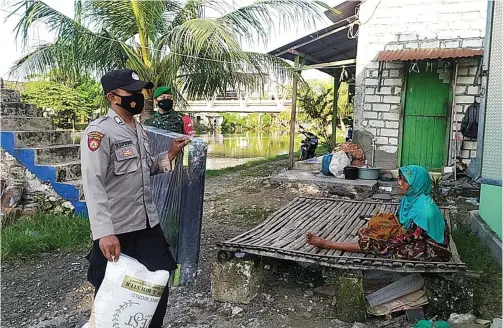  ?? POLRES GRESIK FOR JAWA POS ?? EMPATI: Bripka Hadi Supriyanto dan Serda Marjuki mendatangi rumah Mbah Maruji di Desa Sembayat, Manyar, untuk memberikan bantuan berupa kasur dan bantal.