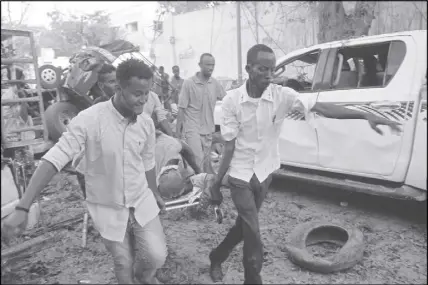  ?? AP PHOTO ?? Somalis carry away the wounded civilian who was injured in a car bomb that was detonated in Mogadishu, Somalia. A suicide car bomb exploded outside a popular hotel in Somalia’s capital on Saturday.