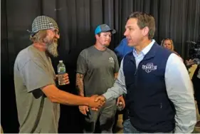  ?? AP PHOTO/CHARLIE NEIBERGALL ?? Republican presidenti­al candidate Florida Gov. Ron DeSantis, right, greets a worker Wednesday during a campaign event at Port Neal Welding in Salix, Iowa.
