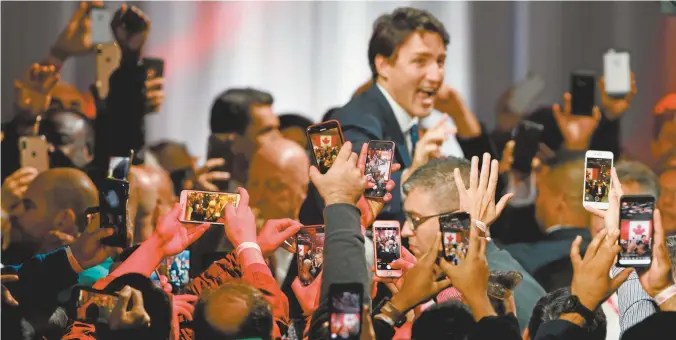  ??  ?? Voters photograph re-elected Canadian Prime Minister Justin Trudeau as he prepares to make his victory speech.