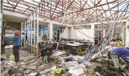  ?? AARON FAVILA/AP ?? Workers clear debris from Typhoon Haiyan at the damaged Expert Global Solutions call center in Palo, Leyte, central Philippine­s.