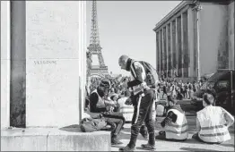  ?? GEOFFROY VAN DER HASSELT/GETTY-AFP ?? Yellow vest activists take up spots in front of the Eiffel Tower on Saturday before taking part in a protest against France’s economic policies for the 20th straight weekend.