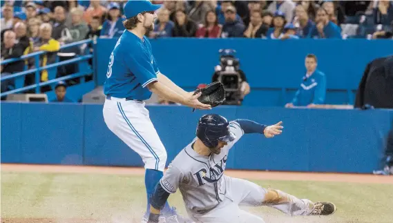  ??  ?? Kevin Kiermaier (der.), de Tampa Bay, se desliza en el plato para robárselo aprovechan­do un lanzamient­o descontrol­ado de R.A. Dickey, de Toronto.