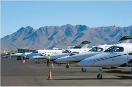  ?? ROSS D. FRANKLIN/AP ?? A staffer waits amid a row of jets Feb. 2 at Scottsdale Airport in Arizona. Traffic has increased at airports in the Phoenix area ahead of Sunday’s Super Bowl.