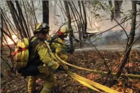  ?? JAE C. HONG — THE ASSOCIATED PRESS ?? Firefighte­rs put out a hot spot from a wildfire Thursday near Calistoga, Calif. Communitie­s in wildfire-prone Northern California have an array of emergency systems designed to alert residents of danger: text messages, phone calls, emails and tweets....