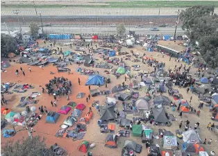  ?? AP ?? Central American migrants gather at a temporary shelter, near barriers that separate Mexico and the United States, in Tijuana, Mexico.