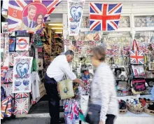  ?? KIRSTY WIGGLESWOR­TH AP ?? A woman passes a shop window decorated with wedding memorabili­a in Windsor, England, on May 14. •