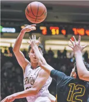  ?? CRAIG FRITZ/FOR THE NEW MEXICAN ?? Española Valley’s Zach Mascareñas passes the ball over Jason Arnett of St. Pius X during Wednesday’s Class 4A state boys basketball tournament game at The Pit. The Sundevils won 61-41.