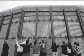  ?? AP/GREGORY BULL ?? Pastors and others on the San Diego side of a border fence participat­e in a cross-border religious service in July with counterpar­ts on the Tijuana, Mexico, side of the fence.