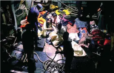  ?? BBXPIX ?? A rescuer talks to one of the three survivors on the fishing boat after they were plucked from the sea. Next to them are the bodies of three victims.