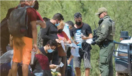  ?? JUAN FIGUEROA/THE DALLAS MORNING NEWS ?? A group of mostly Cuban migrants is met by Border Patrol agents last month after reaching the U.S. via Mexico.