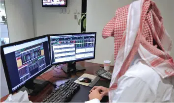  ?? — Reuters ?? A Saudi trader observes the stock market on monitors at Falcom stock exchange agency in Riyadh.