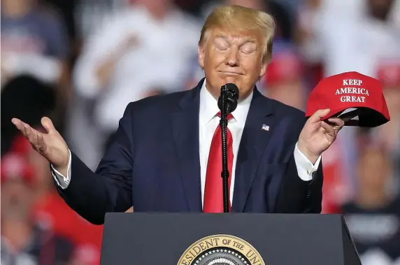  ?? MATT STONE / HERALD FILE PHOTOS ?? ‘LONG GAME’: President Trump holds a hat with his new slogan, ‘Keep America Great,’ during an August rally in New Hampshire.