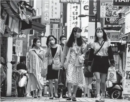  ?? KIM HONG-JI ■ REUTERS ?? People wearing masks walk at Myeongdong shopping district amid social distancing measures to avoid the spread of COVID-19, in Seoul, South Korea.