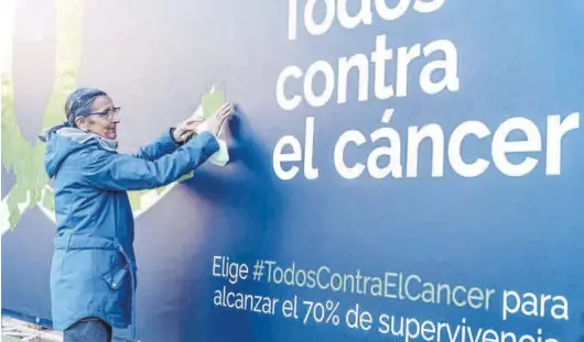  ?? GABRIEL LUENGAS / EUROPA PRESS ?? Una mujer pega una nota con un mensaje de apoyo a la investigac­ión contra el cáncer, en una imagen de archivo.