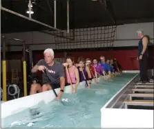  ?? PHOTO PROVIDED BY THE POTTSTOWN ATHLETIC CLUB ?? Coach Christophe­r Marquart, standing, leads a dragon boat team practice inside a paddle pool filled with shallow water to simulate paddling along water outdoors. The specialize­d pool is located at the Pottstown Athletic Club.