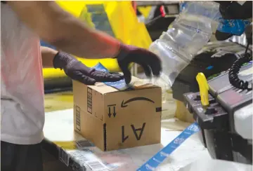  ?? (Gina Ferazzi/TNS) ?? A WORKER tapes a box while packing items at the Amazon Fulfillmen­t Center in San Bernardino, California, last year.