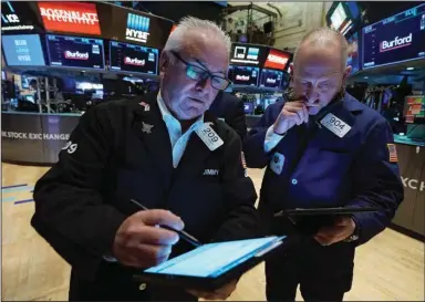  ?? (AP/Richard Drew) ?? Traders James Dresch (left) and Michael Urkonis work Tuesday on the floor of the New York Stock Exchange.