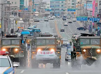  ?? — AFP ?? Military vehicles spray disinfecta­nt as part of preventive measures against the spread of the Covid-19, on a road near Dongdaegu railway station in Daegu, South Korea on Saturday.