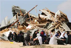  ?? (Ammar Awad/Reuters) ?? BEDUIN WOMEN sit next to the ruins of their dwellings, which were demolished by bulldozers in Umm el-Hiran in January.