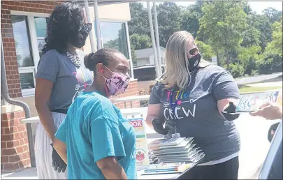  ?? SUBMITTED PHOTO ?? Leslie Smallwood, left, the parent liaison at Dr. Samuel A. Mudd Elementary School, Arin Bonner, center, Title I coordinato­r, and Jennifer Bowling, right, parent liaison with the Title I office, hand out books to visitors at Mudd’s meal site.