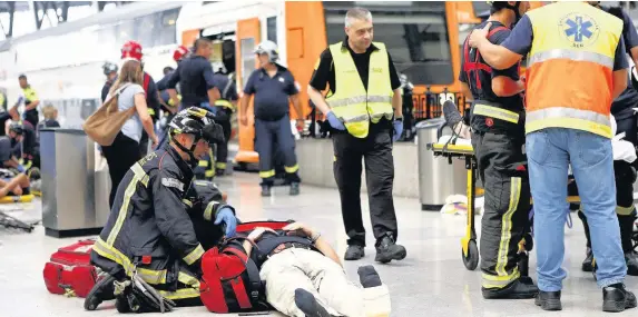  ??  ?? > An injured passenger is attended to on the platform of a train station in Barcelona yesterday after a commuter train crashed into the buffers