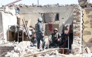  ??  ?? Afghan policemen gather at the site of a suicide bombing attack on the police headquarte­rs in Gardez, capital of Paktia province recently. (AFP)