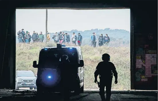  ?? LLIBERT TEIXIDÓ ?? Un grup de persones observen la intervenci­ó dels Mossos d’Esquadra a l’interior de la nau de la Bòbila