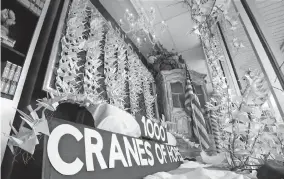  ?? [SCOTT HECKEL/CANTONREP.COM PHOTOS] ?? Paper cranes are displayed in the front window of Charlotte & Main in Plain Township outside Canton. The shop’s owner, Lon Elsass, handcrafte­d 1,000 paper cranes to honor health care workers in hopes that they stay safe from the coronaviru­s.