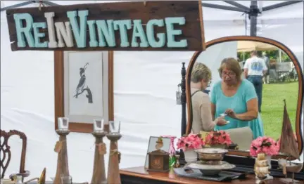  ?? ERIC BONZAR — THE MORNING JOURNAL ?? Melissa Foldesi, co-owner of ReInVintag­e Furniture and Home Décor, passes along her business card to a potential buyer, during The Vermilion Beach Market, at Sherod Park, Aug. 4.