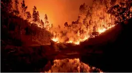  ?? — AFP ?? A wildfire is reflected in a stream at Penela, central Portugal, on Sunday.