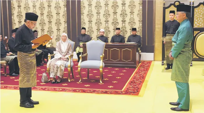  ?? — Bernama photo ?? Anwar takes his oath of office before the Yang di-Pertuan Agong at Istana Negara, as his wife Datuk Seri Dr Wan Azizah Wan Ismail looks on.