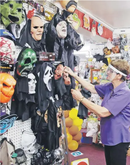  ??  ?? Una empleada con un escudo facial ordena máscaras de Halloween en una tienda de disfraces.