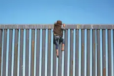  ?? Reuters ?? A migrant climbs the border fence between Mexico and the United States in Tijuana, Mexico, on Sunday.