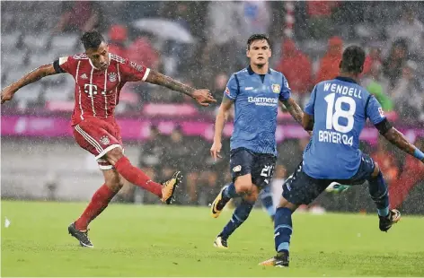  ?? FOTO: DPA ?? Der Münchner Zugang Corentin Tolisso (l.) zieht im strömenden Regen ab, die Leverkusen­er Charles Aranguiz und Wendell können es nicht verhindern.