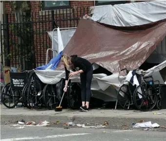  ?? NAncy LAnE pHOTOS / HErALd STAFF ?? ON THE STREETS: A woman sweeps up around wheelchair­s in the area of Mass and Cass covered by a tarp that, like the tents seen at bottom, survived Hurricane Ida’s dousing rain. Acting Mayor Kim Janey, left, is not saying whether the area, which has drawn large numbers of homeless people and addicts, will be subject to an enforcemen­t soon.