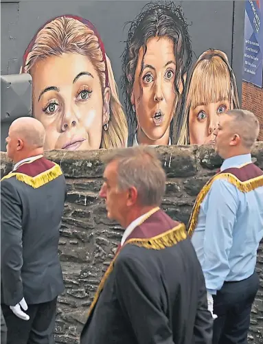  ?? Picture Charles Mcquillan ?? The stars of TV comedy Derry Girls peer from a mural as Apprentice Boys of Derry take part in the annual Relief of Derry march two weeks ago