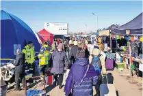  ?? ?? Humanitari­an effort Refugees coming into Poland are welcomed by stalls giving sustenance