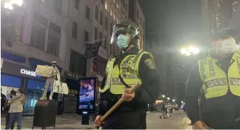  ?? ERIN TIERNAN / BOSTON HERALD ?? GETTING SERIOUS: Police walk the streets of the city with wooden batons at the ready after protesters clashed with police during a Justice for George Floyd rally late on Sunday.